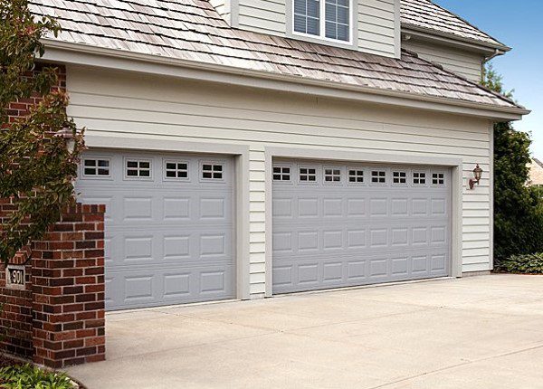 A couple of gray garage doors in front of a house.