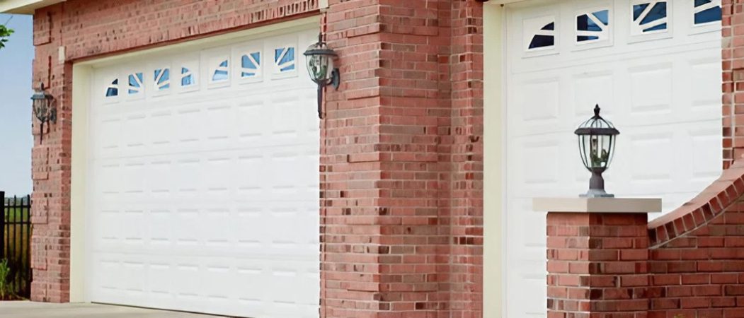 A brick wall with two garage doors and one door is open.