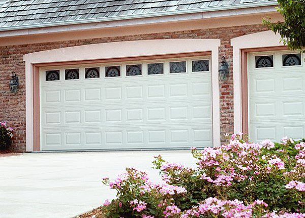 A garage door with flowers in front of it.