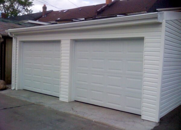 A white garage door is open on the side of a house.